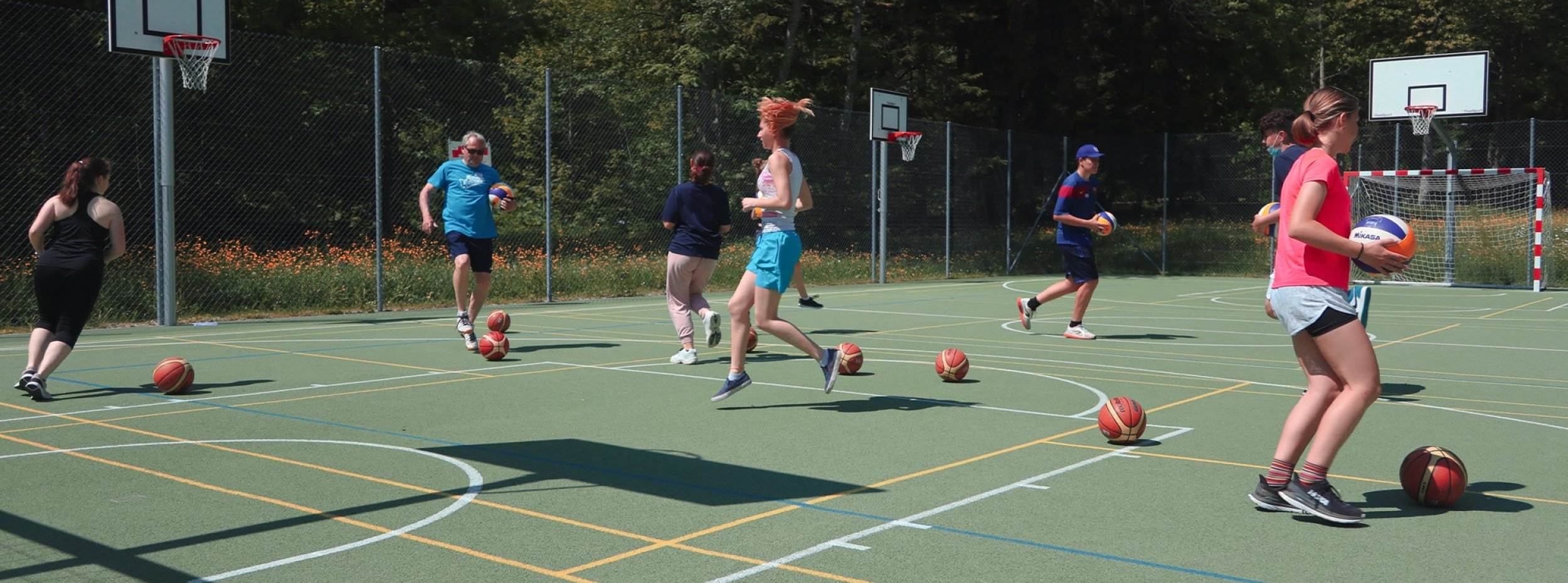 Des personnes jouent sur un terrain de basket extérieur